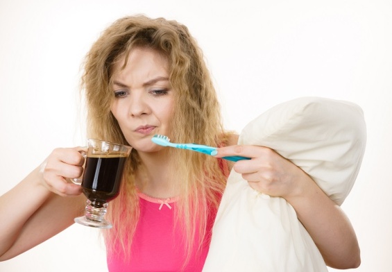 woman holding toothbrush and coffee